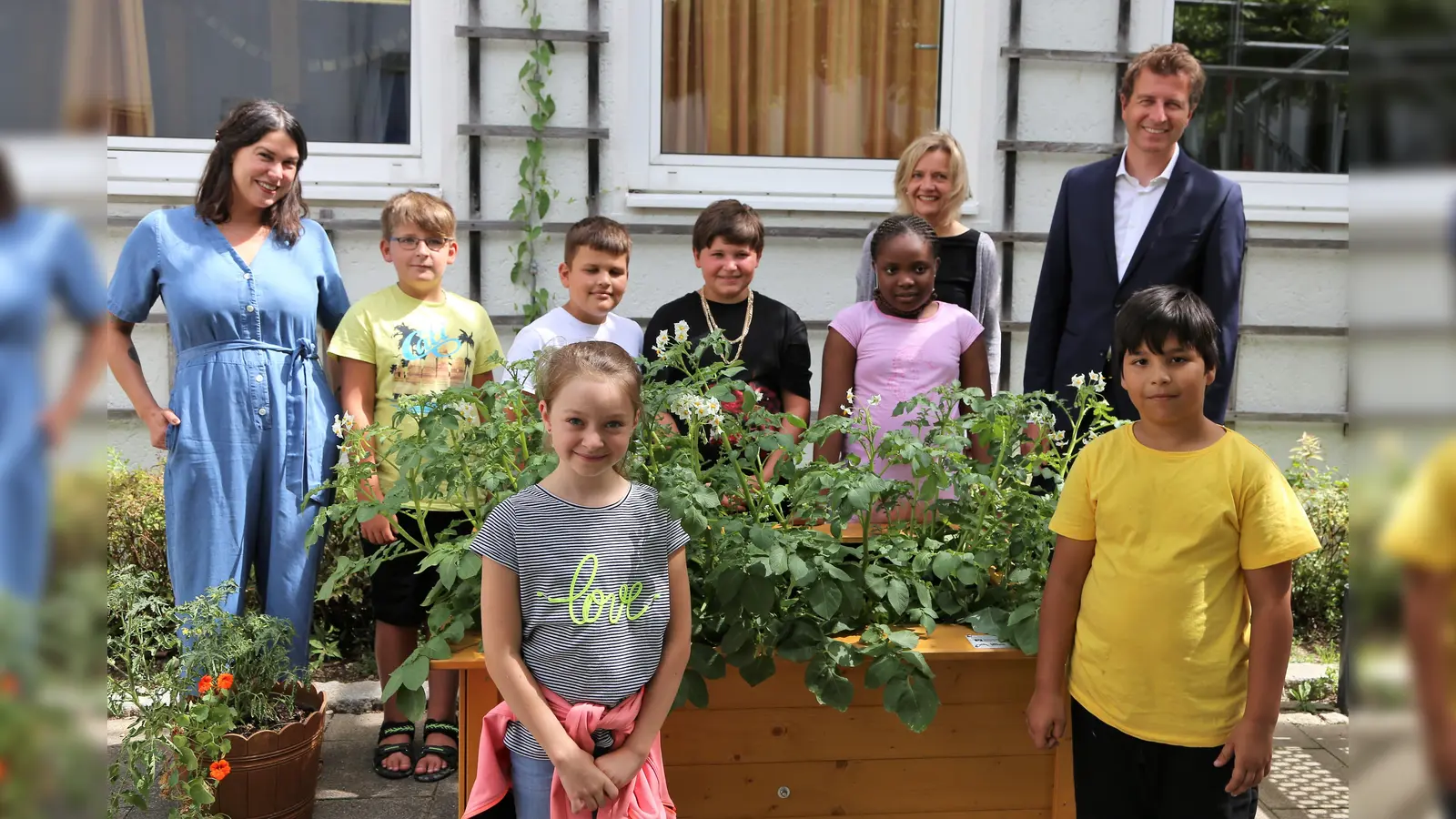 Ganztagspädagogin Marion Reiss (li), Schulleiterin Viktoria Ledermann und Bankvorstand Klaus Berger mit den Kindern der Greta-Fischer-Schule vor einem der beiden Hochbeete.  (Foto: VR Bank Dachau)
