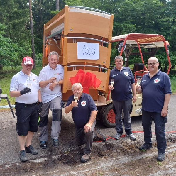 Anton Gutmann, Hans Neugschwendner vom BRK-Kreisverband Neuburg-Schrobenhausen, Hans Ramsteiner, Jörg Zimmermann und Andreas Millik vom BRK-Kreisverband Dachau stoßen auf das tausendste gespendete und in die Ukraine transportierte Bett an. (Foto: BRK)
