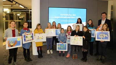 Stolz präsentieren die Kinder und Jugendlichen den Jugendmalkalender 2023 mit Bankvorstand Klaus Berger. (Foto: VR Bank)
